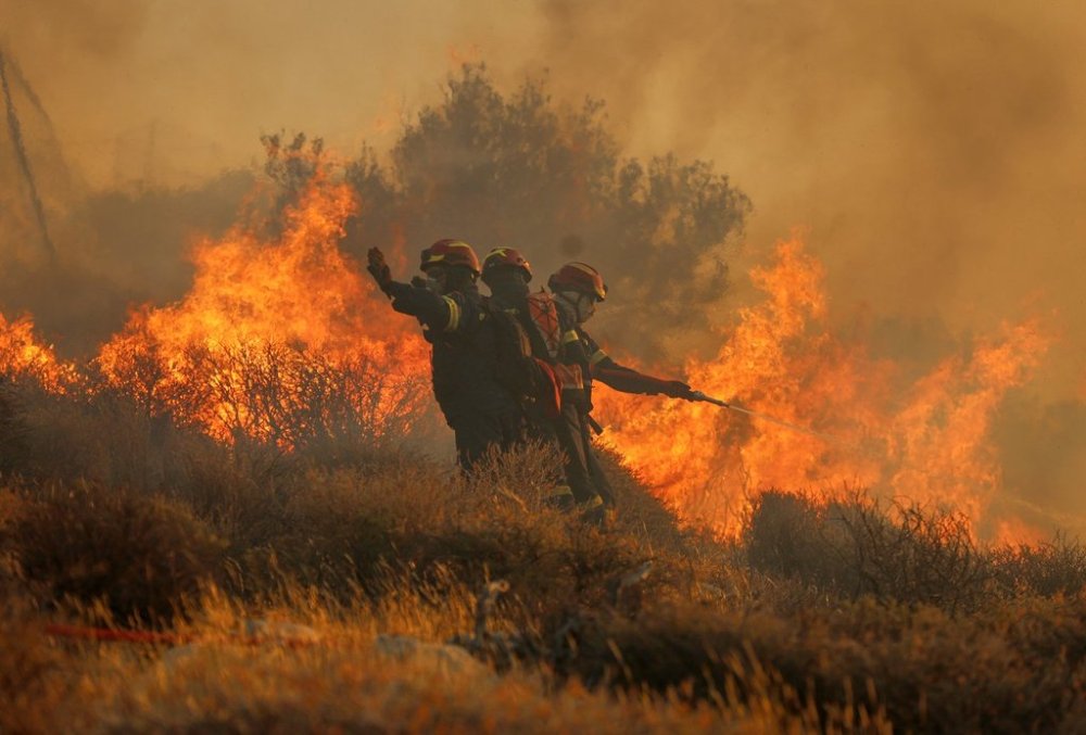 Firefighter uses a hose as the try to extinguish the blaze near the town of Ierapetra on the south coast of Crete island, Greece, Thursday July 3, 2025, as a fast-moving wildfire prompted authorities to clear villages and coastal areas, officials said. (InTime News via AP)