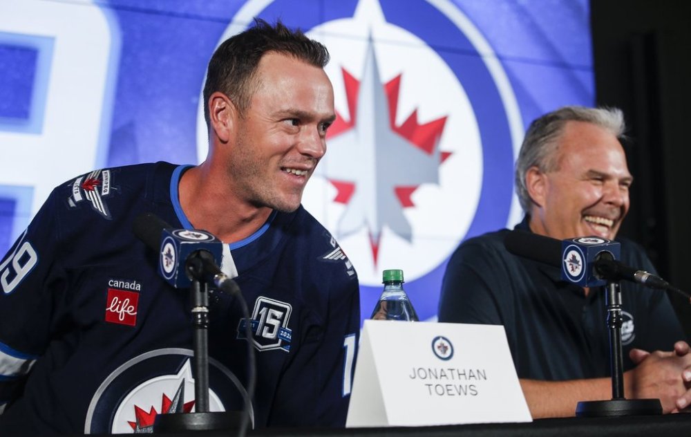 Winnipeg Jets executive vice president and general manager Kevin Cheveldayoff, right, and Jonathan Toews laugh during a press conference held to welcome Toews to the team in Winnipeg on Friday, July 4, 2025. THE CANADIAN PRESS/John Woods