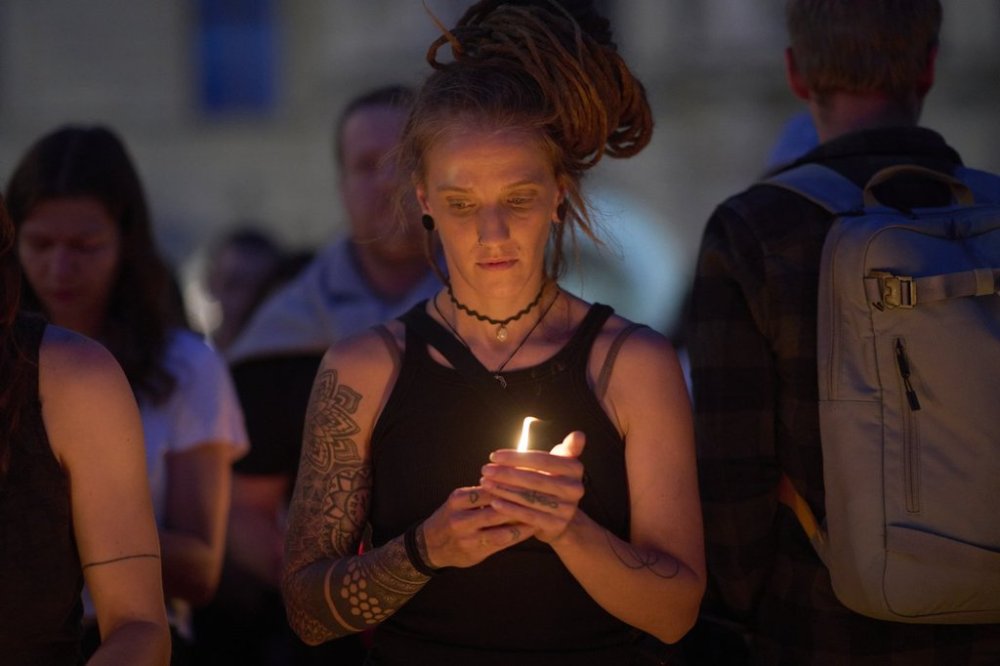 A woman holds a candle for victims of a former student who opened fire at a school, fatally wounding 10 people and injuring many others before taking his own life, in Graz, Austria, Tuesday, June 10, 2025. (AP Photo/Darko Bandic)
