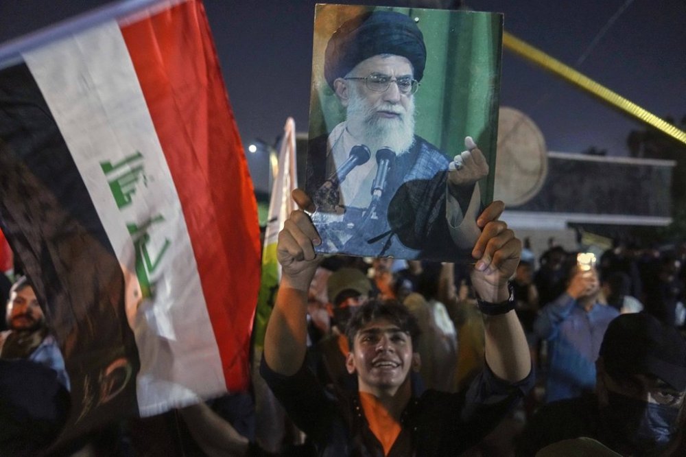 A protest holds a portrait of Iran's Supreme Leader Ayatollah Ali Khamenei during a protest against Israeli attacks on multiple cities across Iran, at a bridge leading to the fortified Green Zone where the U.S. embassy is located in Baghdad, Iraq, Saturday, June 14, 2025. (AP Photo/Hadi Mizban)