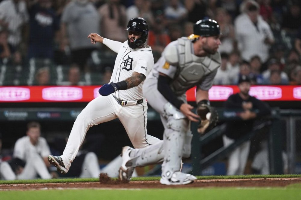 Detroit Tigers' Gleyber Torres, left, scores around Athletics catcher Austin Wynns, right, in the eighth inning during a baseball game, Tuesday, June 24, 2025, in Detroit. (AP Photo/Paul Sancya)