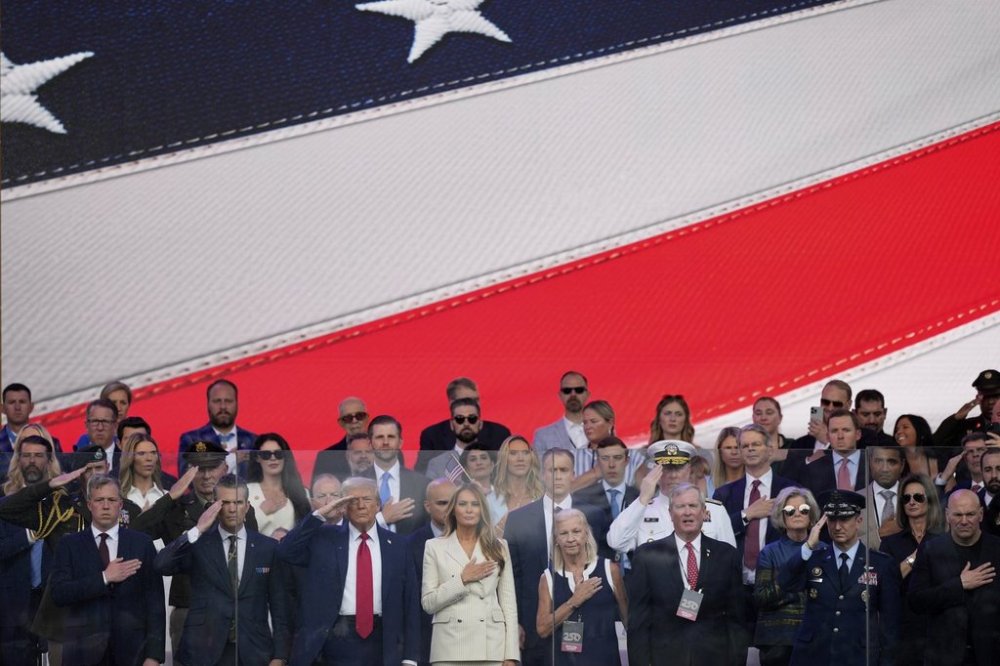 President Donald Trump, first lady Melania Trump, and other guests stand for the National Anthem, during a military parade commemorating the Army's 250th anniversary, coinciding with his 79th birthday, Saturday, June 14, 2025, in Washington. (AP Photo/Julia Demaree Nikhinson)