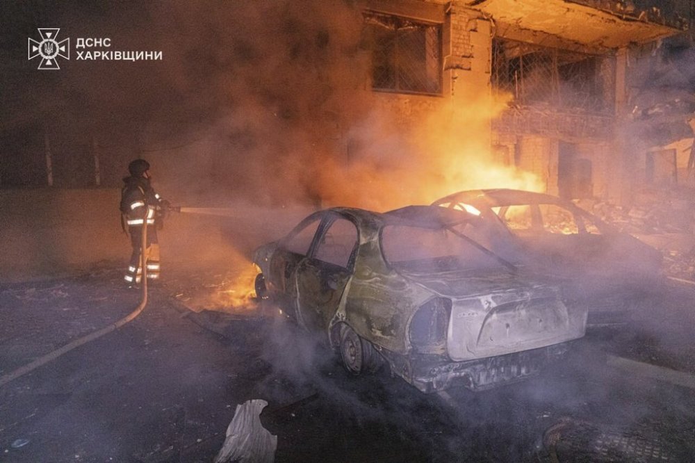 In this photo provided by the Ukrainian Emergency Services on Thursday, June 12, 2025, a rescue worker puts out a fire of a car near a building which was damaged by a Russian strike in Kharkiv, Ukraine. (Ukrainian Emergency Services of Ukraine via AP)