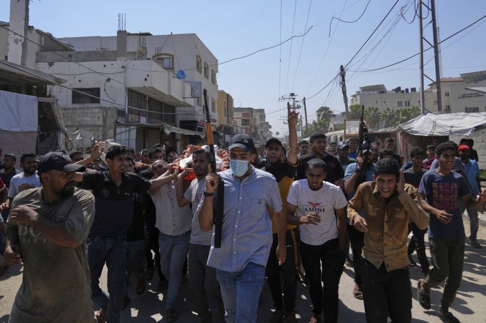 Palestinians, some armed, carry the body of Farouq Khattab, 29, who was killed in an Israeli army airstrike of the Gaza Strip, during his funeral in Deir al-Balah, Wednesday, July 2, 2025. (AP Photo/Abdel Kareem Hana)