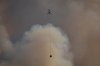 A helicopter with a water bucket flies past smoke rising into the air while battling the July Mountain wildfire along the Coquihalla Highway south of Merritt, B.C., on August 11, 2021. THE CANADIAN PRESS/Darryl Dyck