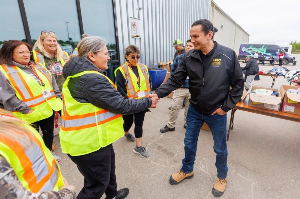 Manitoba Premier Wab Kinew meets with staff from the Manitoba Metis Federation outside the evacuation centre at the Thompson Regional Community Centre in Thompson, Man. during a tour of wildfires in northern Manitoba on Thursday, June 12, 2025. THE CANADIAN PRESS/Mike Deal-Pool