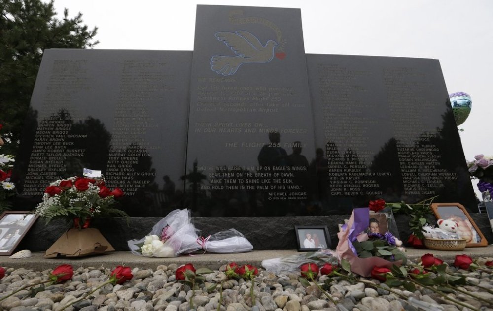 FILE - Flowers and pictures are shown at the memorial in Romulus, Mich., to mark the 25th anniversary of the crash of Northwest Airlines Flight 255 near Detroit Metropolitan Airport, Aug. 16, 2012. The MD-80 aircraft crashed in the Detroit suburb of Romulus, killing all 154 people aboard, except for a 4-year-old girl. Two people also died on the ground. (AP Photo/Paul Sancya, File)