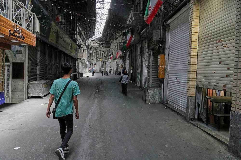 Few pedestrians walk along the historic Grand Bazaar as shops remain shuttered, in Tehran, Iran, Monday, June 16, 2025. (AP Photo/Vahid Salemi)