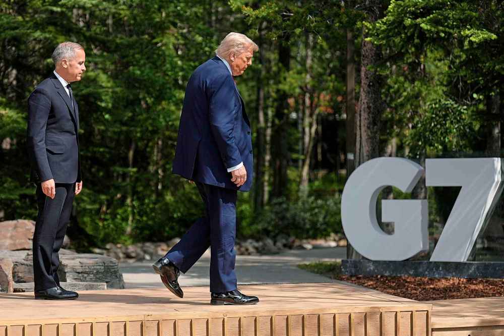 Canada's Prime Minister Mark Carney, left, walks with President Donald Trump during the official welcome of the G7 Summit, Monday, June 16, 2025, in Kananaskis, Canada. (AP Photo/Mark Schiefelbein)