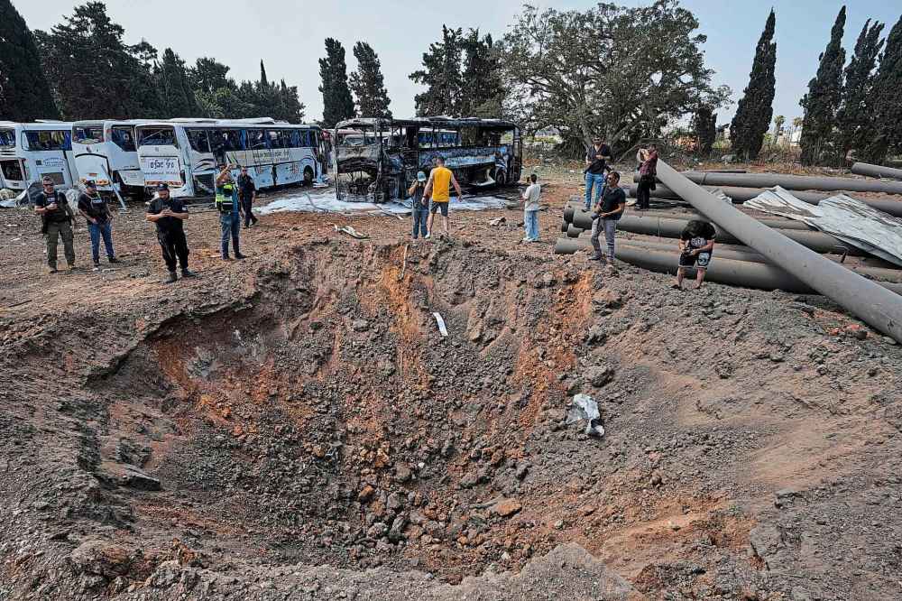 Israeli security forces inspect a site hit by a missile launched from Iran in central Israel on Tuesday, June 17, 2025. (AP Photo/Baz Ratner)