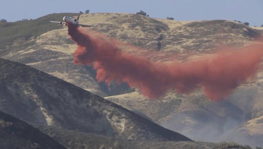 In this image taken from video shows a plane dropping fire retardant the Madre Fire in southeastern San Luis Obispo County, central Calif., July 2, 2025. (KEYT via AP)