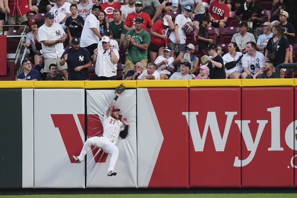 Cincinnati Reds right fielder Jake Fraley (27) falls into the wall after catching a fly ball hit by New York Yankees' Paul Goldschmidt during the fifth inning of a baseball game, Monday, June 23, 2025, in Cincinnati. (AP Photo/Joshua A. Bickel)