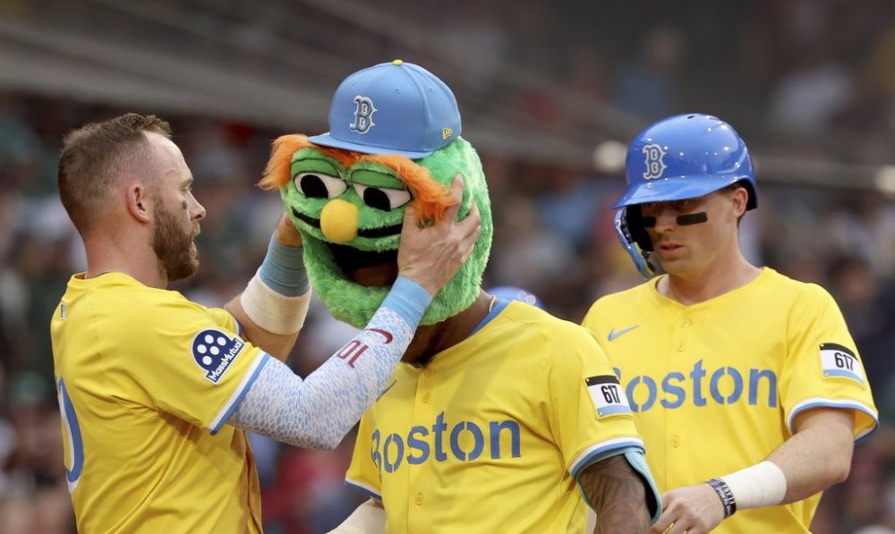 Boston Red Sox's Trevor Story, left, places a mascot head on teammate Ceddanne Rafaela after Rafaela hit a home run during the sixth inning of a baseball game against the Toronto Blue Jays, Saturday, June 28, 2025, in Boston. (AP Photo/Mark Stockwell)