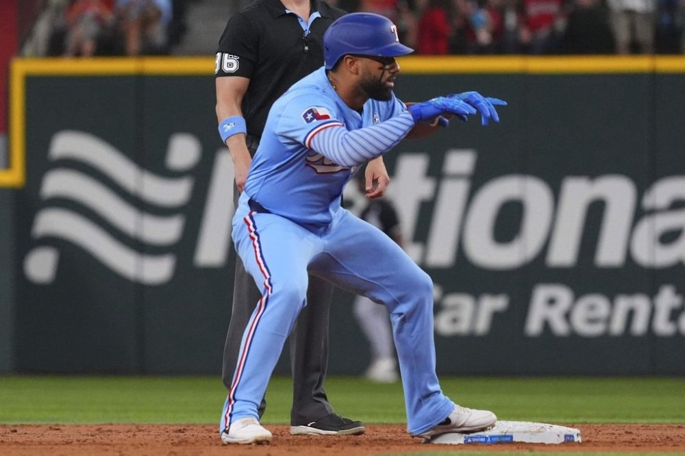 Texas Rangers' Ezequiel Duran, front, stands on second base and reacts after hitting a double that scored teammate Adolis García during the second inning of a baseball game against the Chicago White Sox, Sunday, June 15, 2025, in Arlington, Texas. (AP Photo/LM Otero)