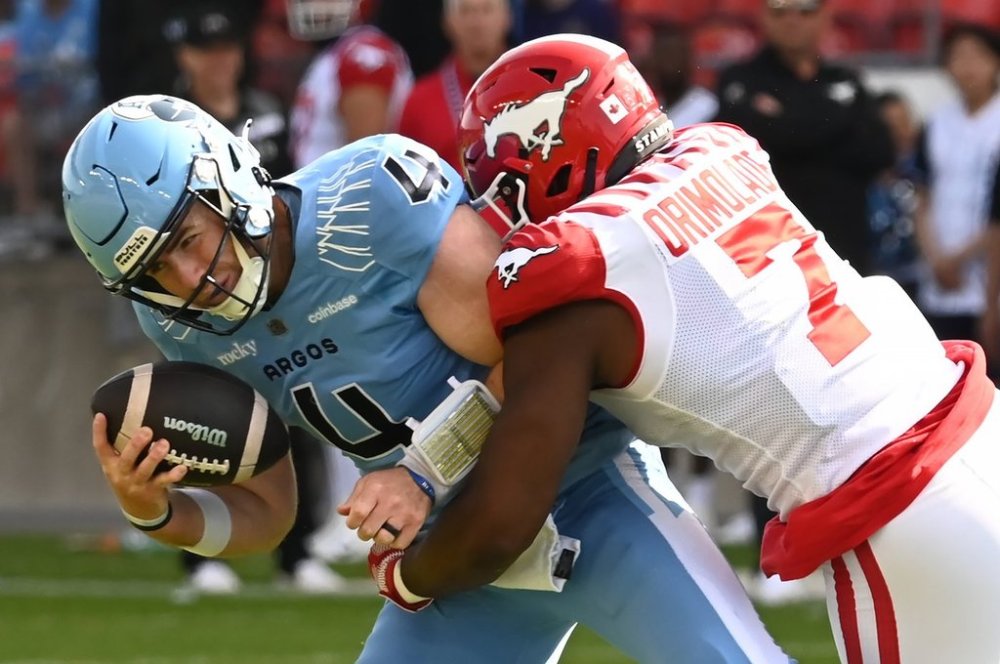 Toronto Argos quarterback Nick Arbuckle (4) is sacked by Calgary Stampeders defensive lineman Folarin Orimolade (7) during first half CFL football action in Toronto, Saturday, June 14, 2025. THE CANADIAN PRESS/Jon Blacker