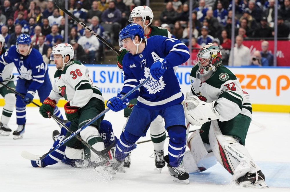 Toronto Maple Leafs winger Mitch Marner (front centre) is checked as he screens Minnesota Wild goaltender Filip Gustavsson (32) during second period NHL hockey action in Toronto on Wednesday, Jan. 29, 2025. THE CANADIAN PRESS/Frank Gunn