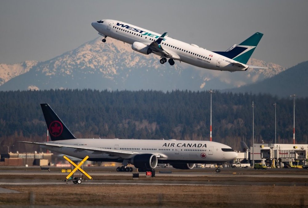 An Air Canada flight taxis to a runway as a WestJet flight takes off at Vancouver International Airport, in Richmond, B.C., on Friday, March 20, 2020. THE CANADIAN PRESS/Darryl Dyck