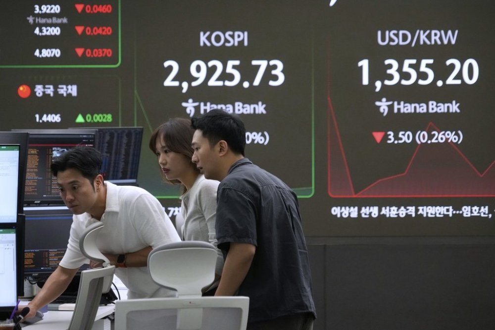 Currency traders watch monitors near a screen showing the Korea Composite Stock Price Index (KOSPI) and the foreign exchange rate between U.S. dollar and South Korean won, right, at the foreign exchange dealing room of the KEB Hana Bank headquarters in Seoul, South Korea, Friday, June 13, 2025. (AP Photo/Ahn Young-joon)