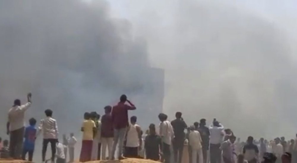 People watch smoke rising after an airplane crashed in Ahmedabad, Gujarat state, India, Thursday, June 12, 2025. (Mohan Nakum via AP)