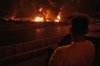 A man looks at flames rising from an oil storage facility after it was hit by an Israeli strike in Tehran, Iran, early Sunday, June 15, 2025. (AP Photo/Vahid Salemi)