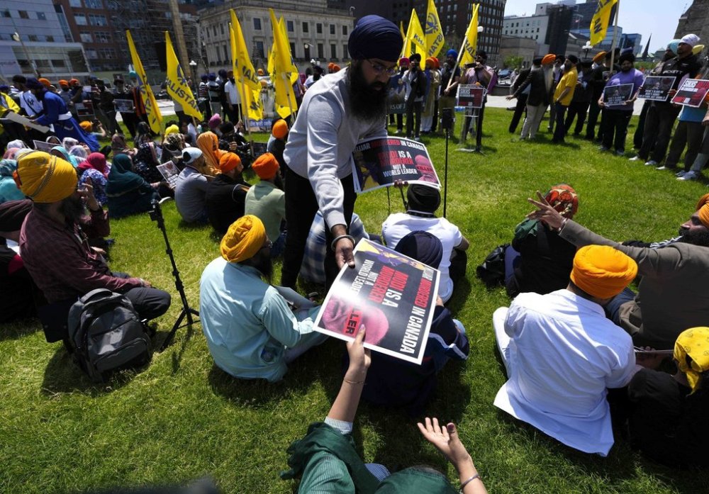 Posters are handed out as people participate in a protest organized by Sikh groups against the visit of Indian Prime Minister Narendra Modi to Canada for the G7 Summit, on Parliament Hill in Ottawa, on Saturday, June 14, 2025. THE CANADIAN PRESS/Justin Tang