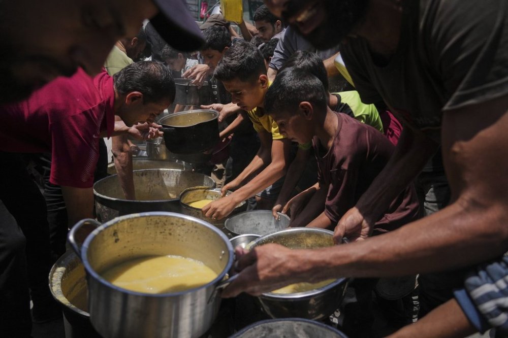 Palestinians receive donated food at a community kitchen in Gaza City, Tuesday, June 10, 2025. (AP Photo/Jehad Alshrafi)