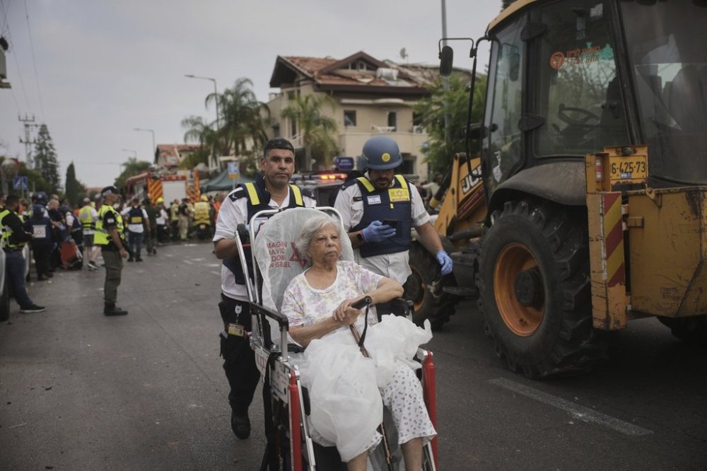 Paramedics evacuate a woman from a site that was struck by a missile fired from Iran, in Rishon Lezion, Israel, on Saturday, June 14, 2025. (AP Photo/Ohad Zwigenberg)