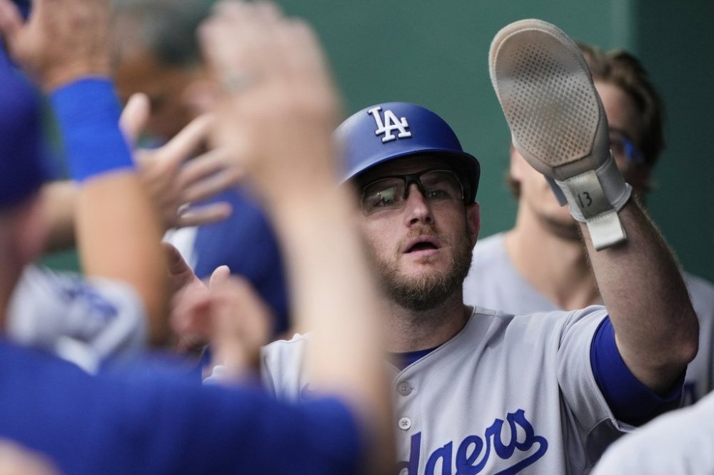 Los Angeles Dodgers' Max Muncy celebrates in the dugout after scoring on a single by Miguel Rojas during the seventh inning of a baseball game against the Kansas City Royals, Sunday, June 29, 2025, in Kansas City, Mo. (AP Photo/Charlie Riedel)
