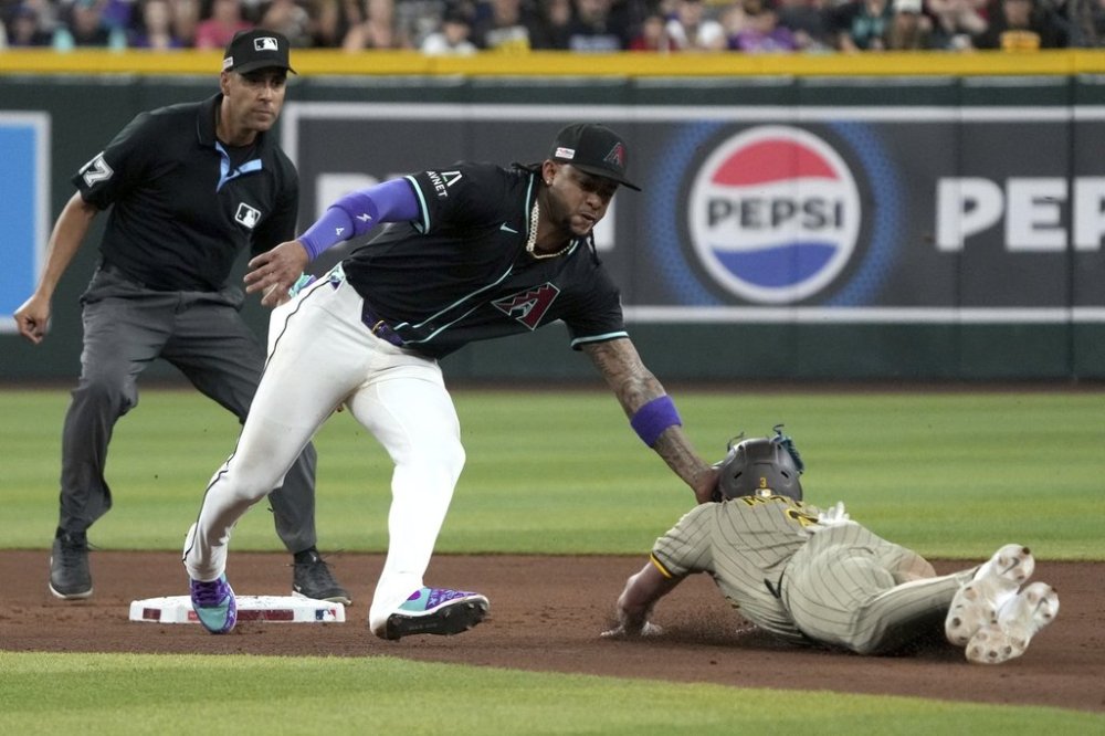 Arizona Diamondbacks second baseman Ketel Marte, center, tags out San Diego Padres' Jackson Merrill, right, who was trying to steal second in the seventh inning during a baseball game, Saturday, June 14, 2025, in Phoenix. (AP Photo/Rick Scuteri)