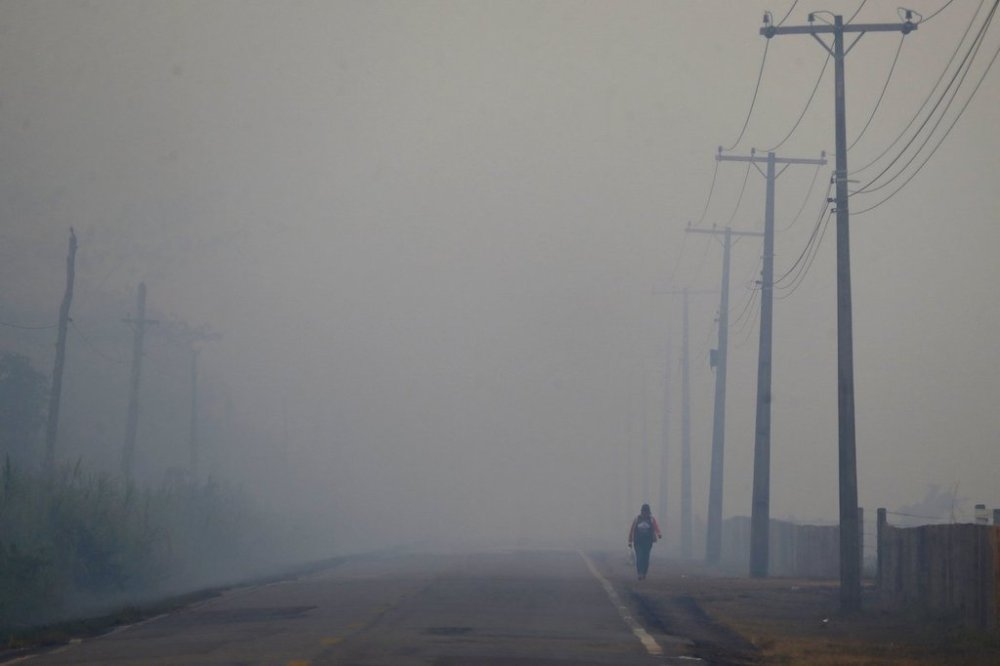 FILE - A person walks on the BR-319 highway through smoke from a forest fire that reaches Careiro Castanho in Brazil's Amazonas state, Sept. 6, 2023. (AP Photo/Edmar Barros, File)