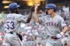 Texas Rangers' Adolis García, left, and Evan Carter celebrate after scoring on a single hit by Kyle Higashioka during the fourth inning of baseball game against the Minnesota Twins, Tuesday, June 10, 2025, in Minneapolis. (AP Photo/Matt Krohn)