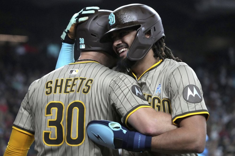 San Diego Padres' Fernando Tatis Jr., right, celebrates with Gavin Sheets (30) after scoring against the Arizona Diamondbacks on a double hit by Luis Arraez in the fifth inning during a baseball game, Sunday, June 15, 2025, in Phoenix. (AP Photo/Rick Scuteri)