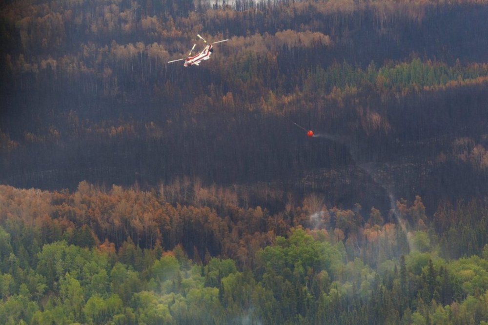 A helicopter crew works on a wildfire in northern Manitoba during a helicopter tour in the surrounding area of Flin Flon, Man. on Thursday, June 12, 2025. THE CANADIAN PRESS/Mike Deal-Pool