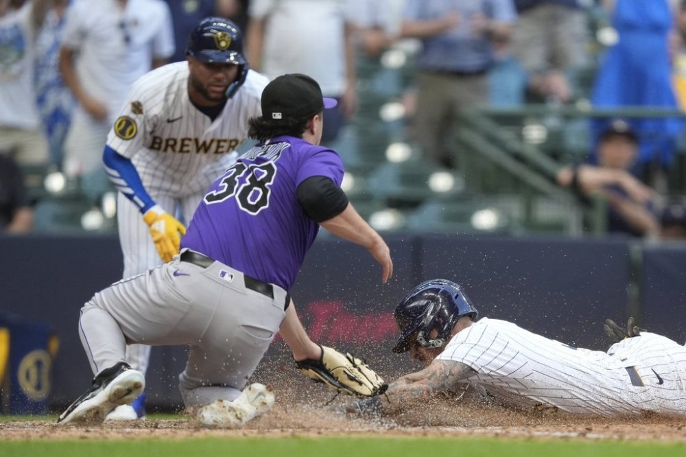Milwaukee Brewers' Joey Ortiz, right, scores on a wild pitch past the tag of Colorado Rockies' Victor Vodnik during the 10th inning of a baseball game, Sunday, June 29, 2025, in Milwaukee. (AP Photo/Aaron Gash)