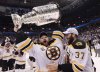 Boston Bruins goalie Tim Thomas hoists the cup with the help of teammate Patrice Bergeron following his teams 4-0 win over the Vancouver Canucks in game 7 of NHL Stanley Cup Final hockey at Rogers Arena in Vancouver, Wednesday, June 15, 2011.  THE CANADIAN PRESS/Jonathan Hayward