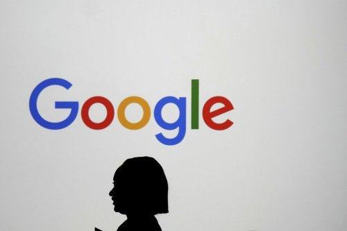 A woman walks by a giant screen with a logo at an event at the Paris Google Lab on the sidelines of the AI Action Summit in Paris on Sunday, Feb. 9, 2025. (AP Photo/Thibault Camus, File)