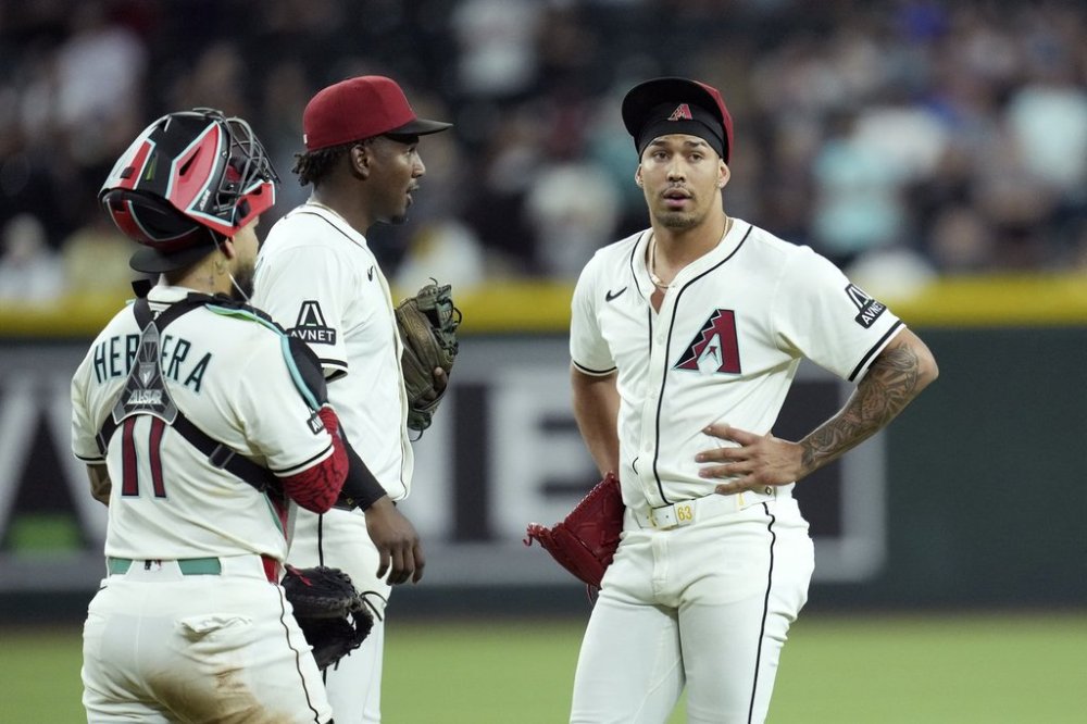 Arizona Diamondbacks pitcher Justin Martinez, right, pauses on the pitcher's mound after an injury as Diamondbacks catcher Jose Herrera, left, and Diamondbacks shortstop Geraldo Perdomo check on Martinez during the ninth inning of a baseball game against the Seattle Mariners Monday, June 9, 2025, in Phoenix. (AP Photo/Ross D. Franklin)