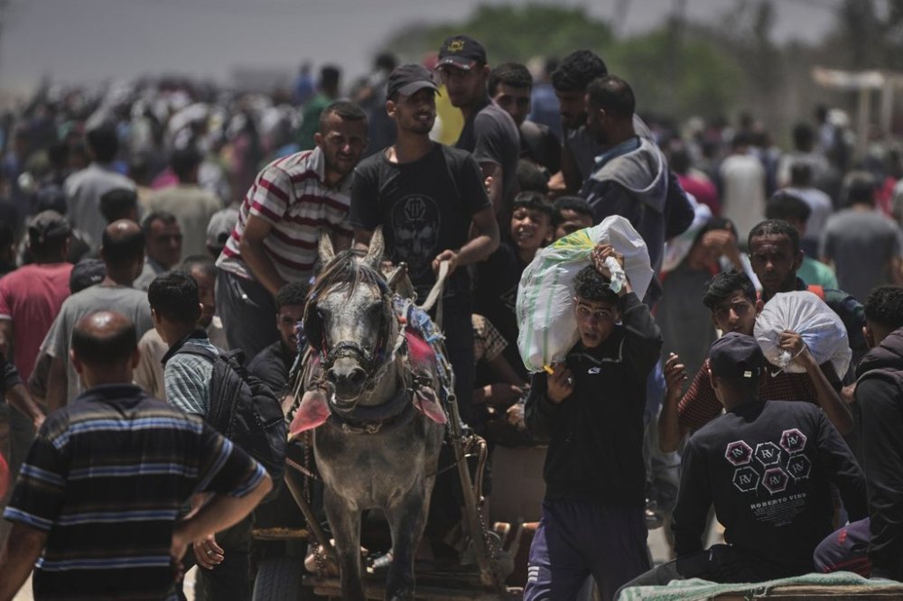Palestinians carry bags containing food and humanitarian aid packages delivered by the Gaza Humanitarian Foundation, a U.S.-backed organization, in Rafah, southern Gaza Strip, Monday, June 9, 2025. (AP Photo/Abdel Kareem Hana)