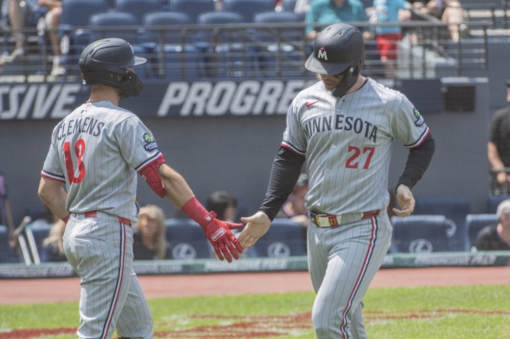 Minnesota Twins' Ryan Jeffers (27) scores on a double by Royce Lewis and is congratulated by Kody Clemens (18) during the first inning of a baseball game, Sunday, Aug. 3, 2025, in Cleveland. (AP Photo/Phil Long)
