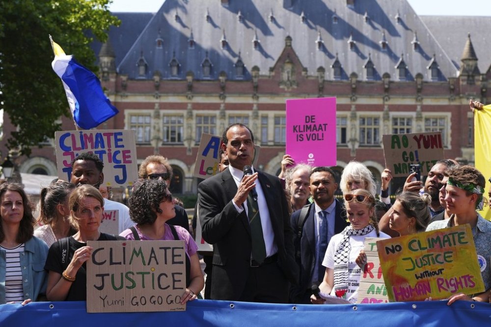 Ralph Regenvanu, Vanuatu's minister for climate change, speaks surrounded by demonstrators as he arrives to the International Court of Justice ahead of an advisory opinion on what legal obligations nations have to address climate change and what consequences they may face if they don't, Wednesday, July 23, 2025, in The Hague, Netherlands. (AP Photo/Peter Dejong)