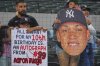 Fans in the stands hold signs before a baseball game between the New York Yankees and the Texas Rangers, Monday, Aug. 4, 2025, in Arlington, Texas. (AP Photo/LM Otero)