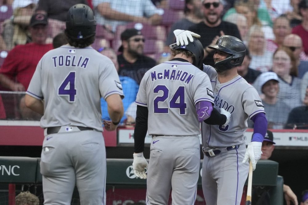 Colorado Rockies' Ryan McMahon, center, celebrates hitting a two-run homer with Kyle Farmer, right, during the fourth inning of a baseball game against the Cincinnati Reds in Cincinnati, Friday, July 11, 2025. Colorado Rockies first baseman Michael Toglia, left also scored. (AP Photo/Carolyn Kaster)