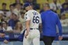 Los Angeles Dodgers relief pitcher Tanner Scott, left, exits the game with trainer Greg Barahas after an apparent arm injury during the ninth inning of a baseball game, against the Minnesota Twins, Monday, July 21, 2025, in Los Angeles. (AP Photo/Jayne Kamin-Oncea)