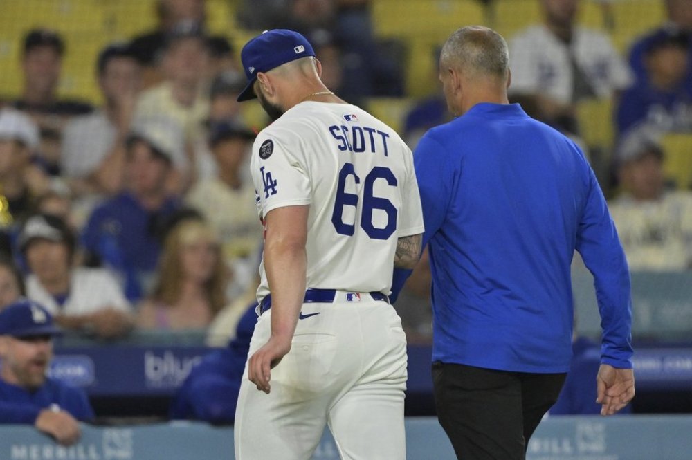 Los Angeles Dodgers relief pitcher Tanner Scott, left, exits the game with trainer Greg Barahas after an apparent arm injury during the ninth inning of a baseball game, against the Minnesota Twins, Monday, July 21, 2025, in Los Angeles. (AP Photo/Jayne Kamin-Oncea)