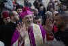 FILE- In this Dec. 24, 2018 file photo, Christians celebrate the arrival of Archbishop Pierbattista Pizzaballa, the top Roman Catholic cleric in the Holy Land, center, after he crossed an Israeli military checkpoint from Jerusalem ahead of midnight Mass at the Church of the Nativity, traditionally recognized by Christians to be the birthplace of Jesus Christ, in the West Bank city of Bethlehem. (AP Photo/Nasser Nasser, File)
