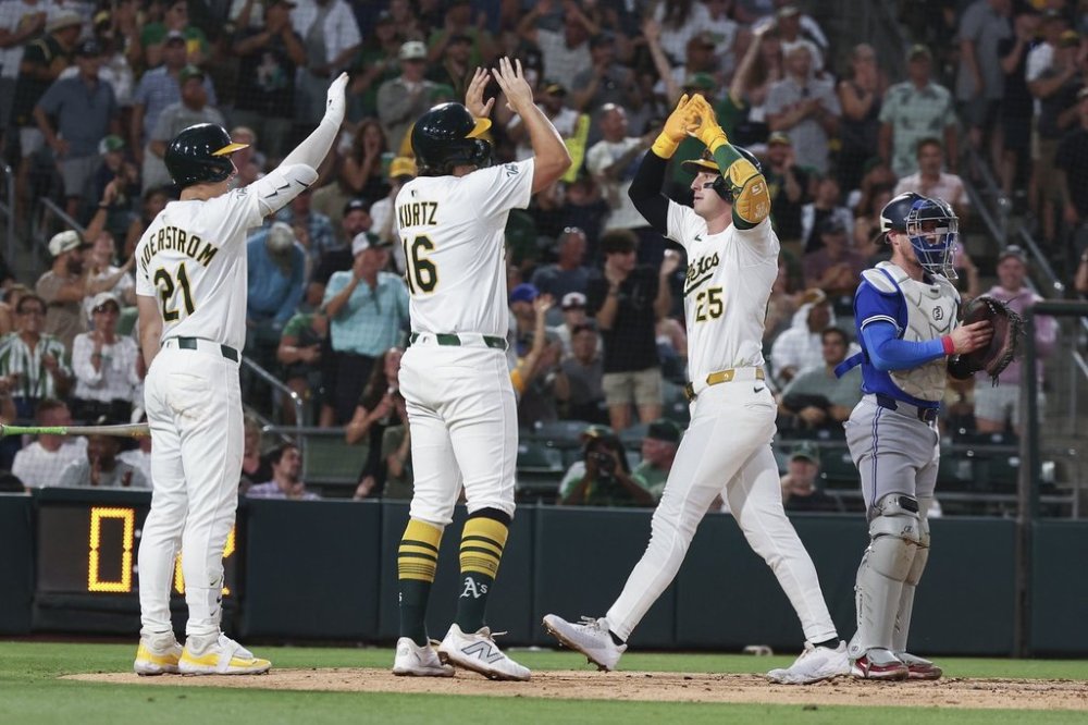 Athletics' Brent Rooker, right, celebrates hitting a two-run home run with Nick Kurtz, centre, and Tyler Soderstrom, left, at home plate during the fifth inning of a baseball game Saturday, July 12, 2025, in West Sacramento, Calif. (AP Photo/Sara Nevis)
