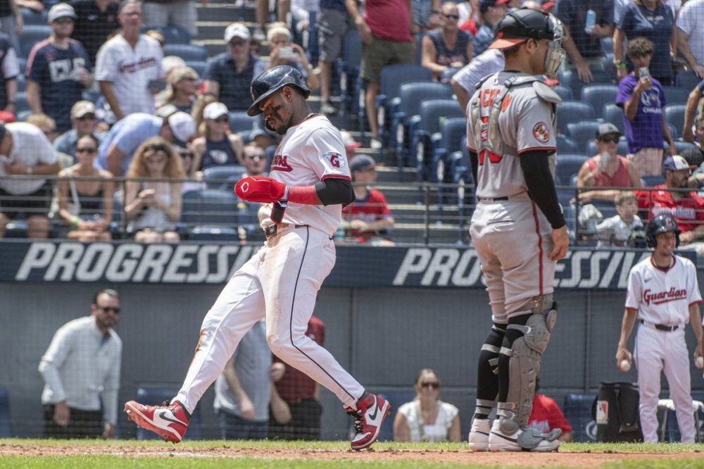 Cleveland Guardians' Angel Martinez, left, scores on a sacrifice fly by Nolan Jones as Baltimore Orioles' Alex Jackson looks towards the field during the third inning of a baseball game, Thursday, July 24, 2025, in Cleveland. (AP Photo/Phil Long)