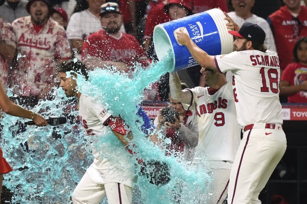 Los Angeles Angels' Travis d'Arnaud, left, s doused with liquid by Zach Neto, center, and Nolan Schanuel after hitting a walk-off single during the ninth inning of a baseball game against the Arizona Diamondbacks, Friday, July 11, 2025 in Anaheim, Calif. (AP Photo/Mark J. Terrill)