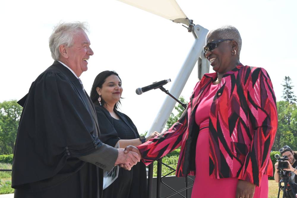 Dionne Clarke, right, shakes hands with Dwight MacAulay, presiding officer of the citizenship ceremony, as she officially becomes a Canadian citizen. (Matthew Frank / Free Press)