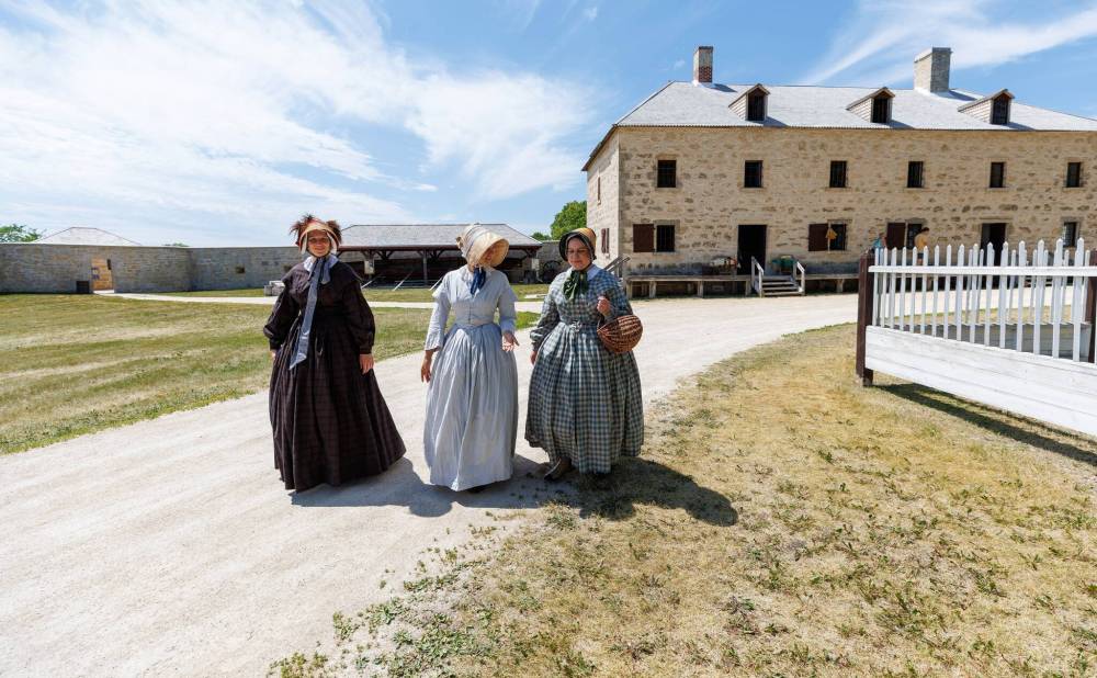 MIKE DEAL / FREE PRESS
Accompanied by Laurie MacDonell (left), Visitor Services Group Supervisor, and Sarah Antymis (centre), Interpretation Coordinator, Jen, now dressed as a higher class lady, makes her way to the Big House where she will have afternoon tea.